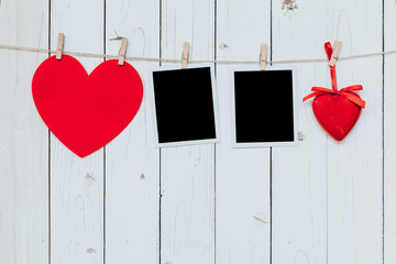 Two photo frame blank and red heart hanging on white wood backgr