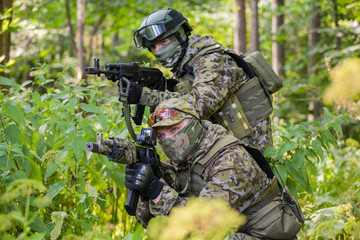 Military man in camouflage with guns in the woods