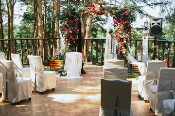White chairs stand before wedding altar on the porch