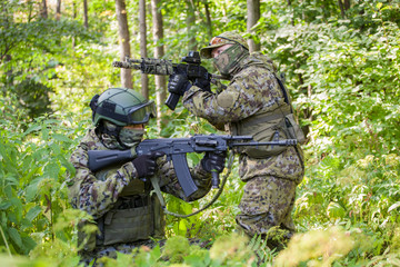 Fototapeta premium Military man in camouflage with guns in the woods