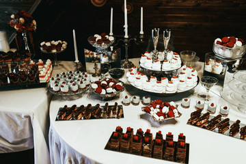 Trays with chocolate cakes and eclairs stand on white table