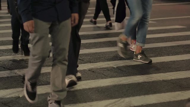DOF: Detail of human legs walking on crowded pedestrian crossing in the evening