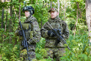 Fototapeta premium Military man in camouflage with guns in the woods