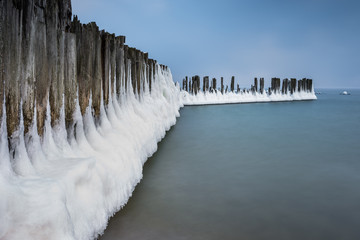 Winter landscape at the sea. Frozen wooden breakwaters line at Baltic Sea. Morning at Babie Doly,...