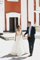 Naklejka premium Happy wedding couple walks around the frontyard of a church in a