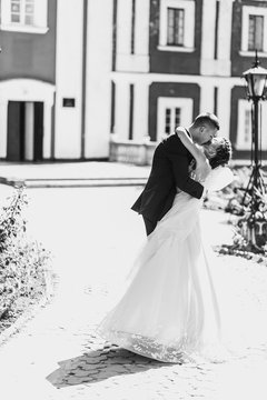 Black and white picture of wedding couple kissing outside in a s