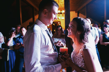 Bride and groom holds burning candle in their hands