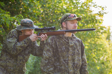 Hunters in camouflage and a gun