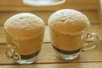 Golden bubble of hot coffee cup placed on a wooden table.