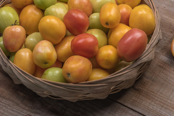 Tomatoes in a natural basket on a rushtic wooden background
