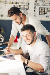 Obraz premium Two designer drawing sketches and looking at tablet screen.