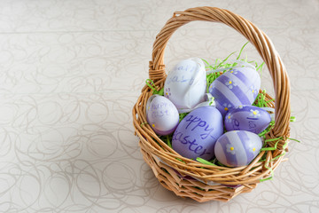 Easter wicker basket with colored eggs on white board.