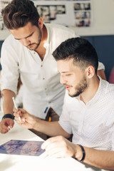 Obraz premium Two designer drawing sketches and looking at tablet screen.