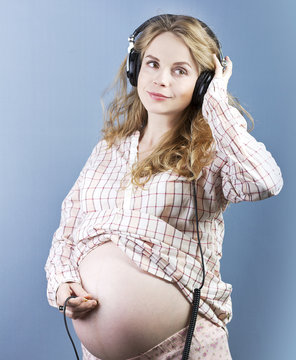 Pregnant woman listens to music. Woman in headphones
