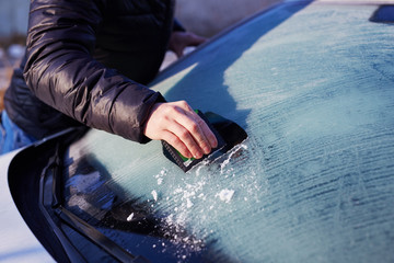 Man scraping ice from the windshield - obrazy, fototapety, plakaty