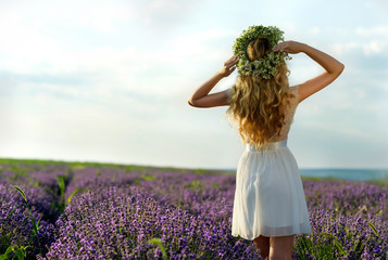 Beautiful Girl in lavender Field. Pretty woman Provence style in white dress and flowers wreath. Beautiful blonde woman in the lavender field on sunset Amazing portrait