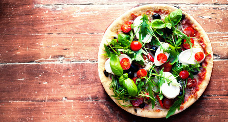 Hot pizza with meat, basil and mozarella cheese on a dark backgr