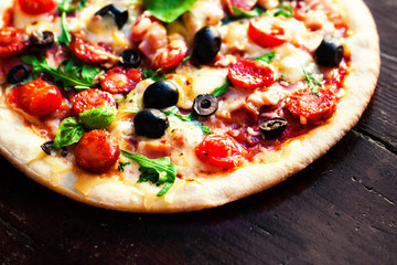 Hot pizza with meat, basil and mozarella cheese on a dark backgr