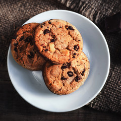 Chocolate chip cookies on white plate dark old wooden table with
