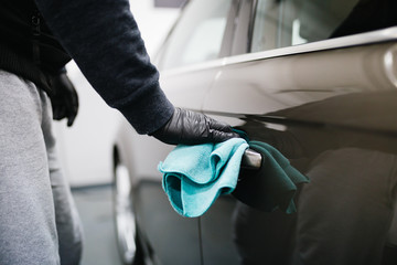 A man cleaning car with microfiber cloth, car detailing (or valeting) concept. Selective focus.