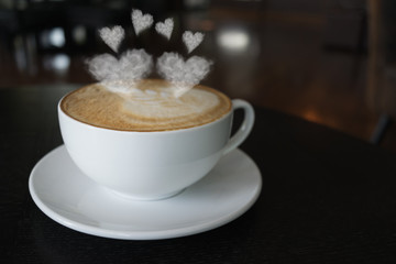 Coffee cup on the table at the coffee shop with heart shaped smoke vintage color tone.