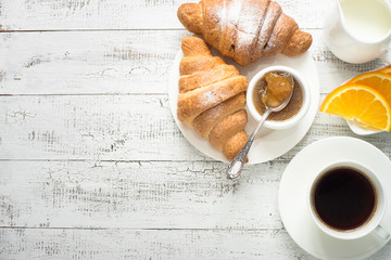 Croissant jam coffee orange juice at white wooden table. Top view with copy space