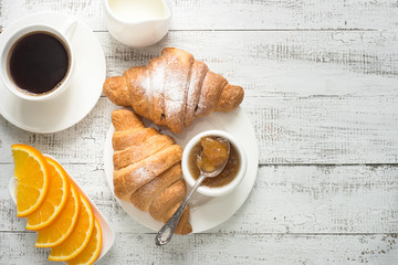 Croissant jam coffee orange juice at white wooden table. Top view with copy space
