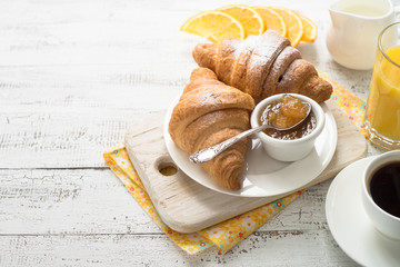 Croissant jam coffee orange jice at white wooden table. 