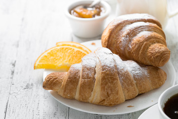 Croissant jam coffee orange at white wooden table.