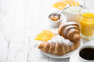Croissant jam coffee orange juice at white wooden table. breakfast