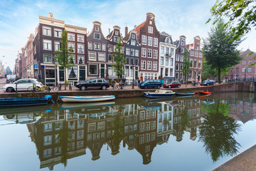 Fototapeta premium Houses and Boats on Amsterdam Canal. Morning photo of colored houses in the Dutch style with reflection in water