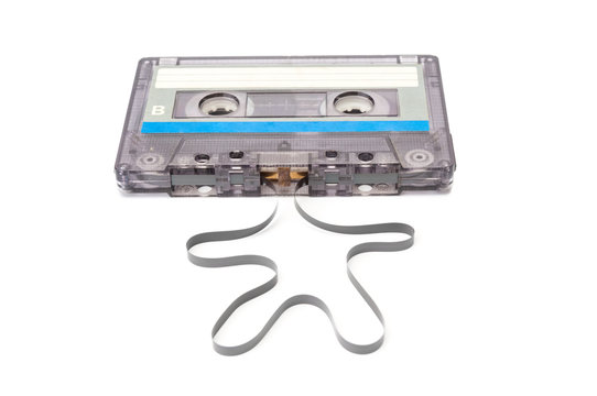 Audio cassette with unwound tape closeup on white background