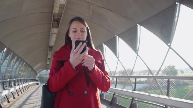 Beautiful woman walking in the city and looking at her smartphone
