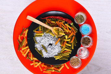plate with pasta, spoon, spices in jars, chili pepper