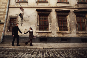 Fototapeta na wymiar young man and woman walks near old building