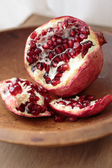 Ripped open fresh ripe pomegranate fruit in a wooden bowl.