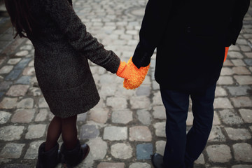 man and woman holding hands in mittens outdoors