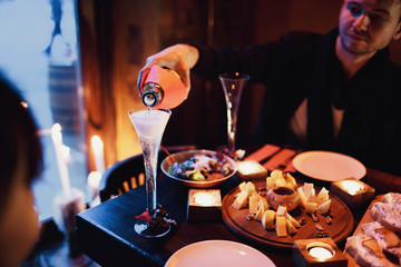  young man pour champagne in glass of his woman