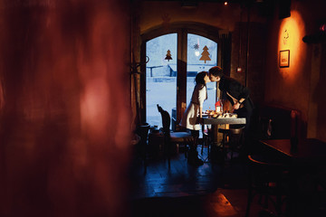 beautiful and young couple kissing in a cozy cafe