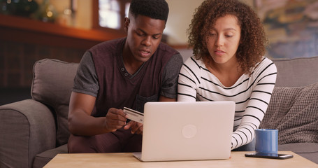 Happy Black millennial couple shopping online