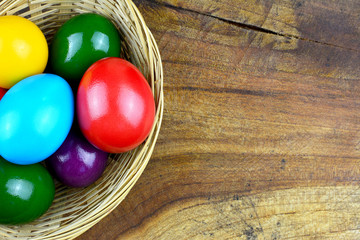 Oster Motiv - Bunte Ostereier im Körbchen am Holztisch mit Textfreiraum