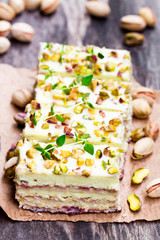 Slices  of layered cake with pistachio on wooden background