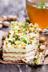 Slices  of layered cake with pistachio and a cup of green herbal