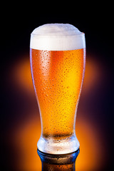 light beer in frosty glass over dark amber background