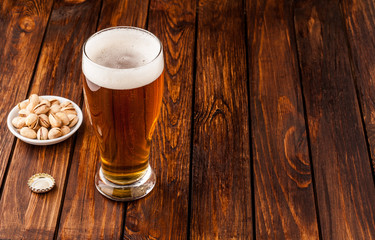 glass of light cold frothy beer, nuts old wooden table