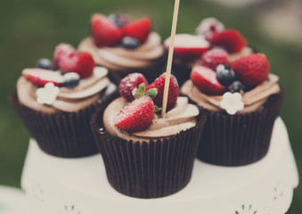 Beautiful cupcakes with berries closeup on banquet table.