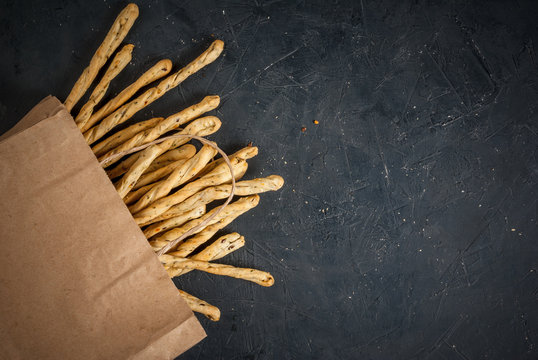 Traditional Italian snack, bread - grizzini. On a dark stone table, copy space