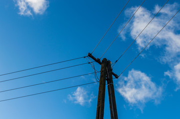 Old power pole with line on blue sky background.