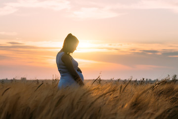 9 months pregnant woman holding belly outdoor sunset. Pregnancy concept.