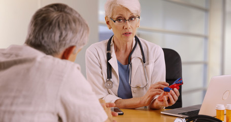 Successful senior woman doctor going over surgery procedure with elderly patient